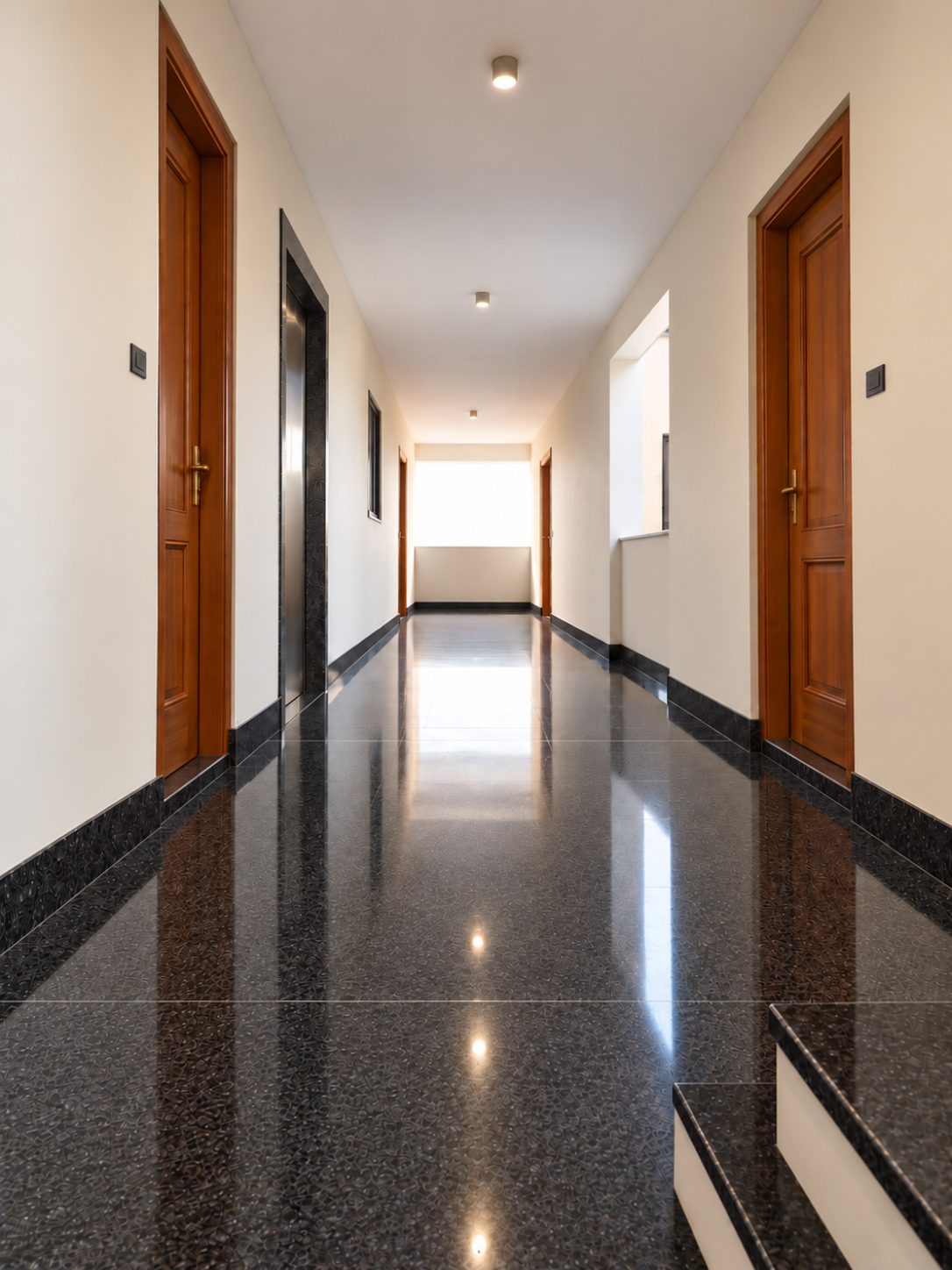 Common corridor with Black Pearl granite floor and skirting, teak doors and the lift opposite the lightwell